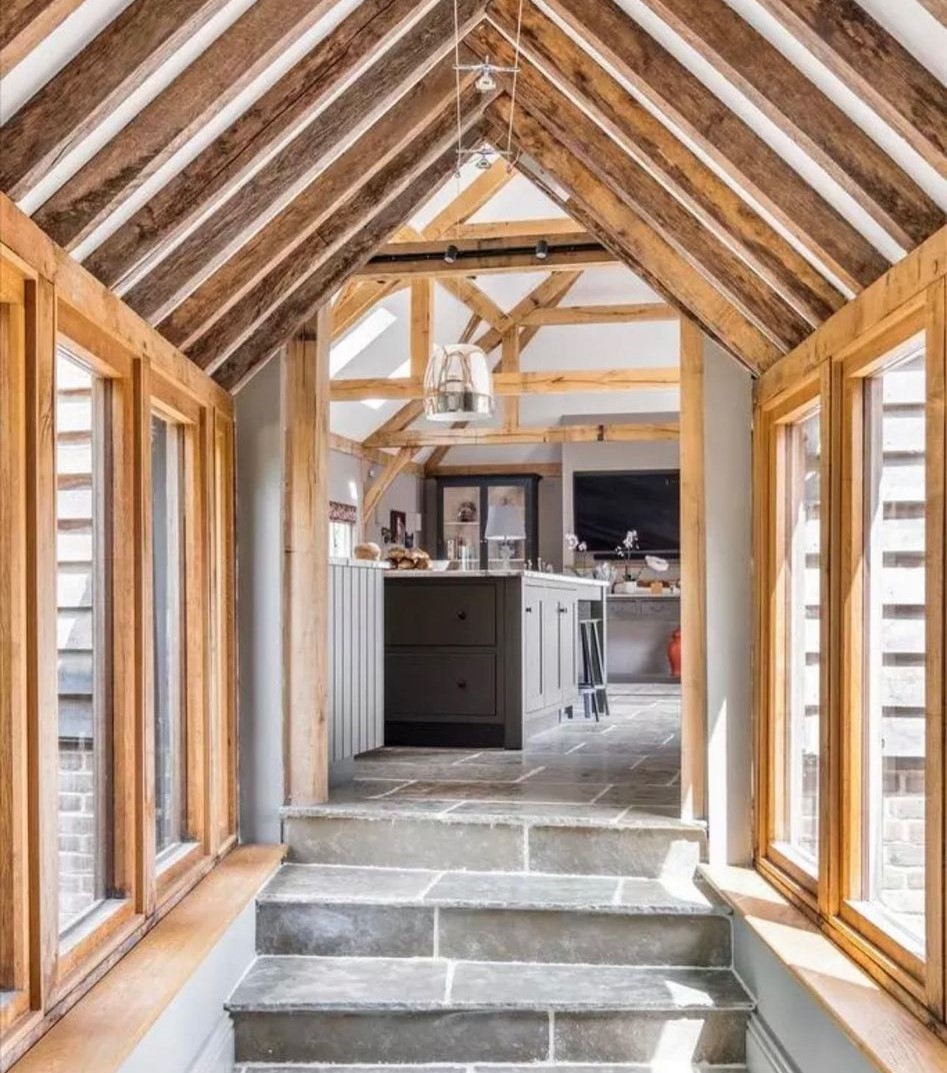 Glazed oak-framed corridor with stone steps leading into a kitchen, pendant light overhead