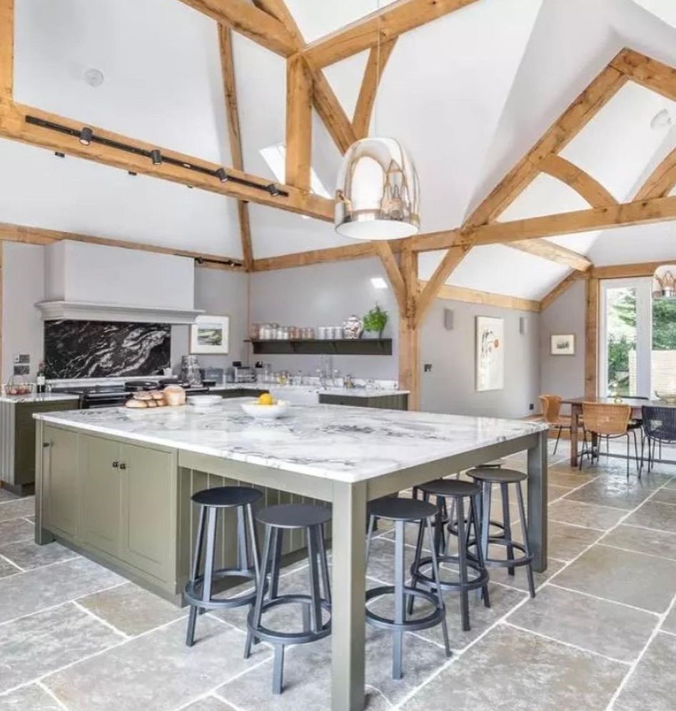 Kitchen island with bar stools under a vaulted oak-beamed ceiling and a polished pendant light